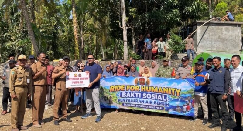 Tim Satgaswil DIY Densus 88 Antiteror Polri bersama aparat desa, TNI-Polri, dan warga membentangkan spanduk saat penyerahan bantuan sarana pompa air dan penyaluran air bersih di Kalurahan Kedungpoh