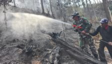 Personel Koramil 11 Kaliwiro bersama warga menyemprot sisa bara api saat proses pendinginan lahan bekas kebakaran di Bukit Bluwuk, Desa Kaliguwo, Kaliwiro, Wonosobo  