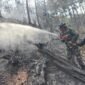 Personel Koramil 11 Kaliwiro bersama warga menyemprot sisa bara api saat proses pendinginan lahan bekas kebakaran di Bukit Bluwuk, Desa Kaliguwo, Kaliwiro, Wonosobo  