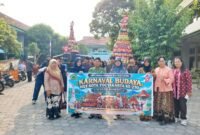 Kepala SMP Taman Dewasa Ibu Pawiyatan Ki Rosidi (keempat dari kiri), pengawas Disdikpora Kota Yogyakarta Retno Puryaningsih (kedua dari kanan), serta jajaran guru dan siswa membentangkan spanduk Karnaval Budaya di halaman sekolah, Yogyakarta